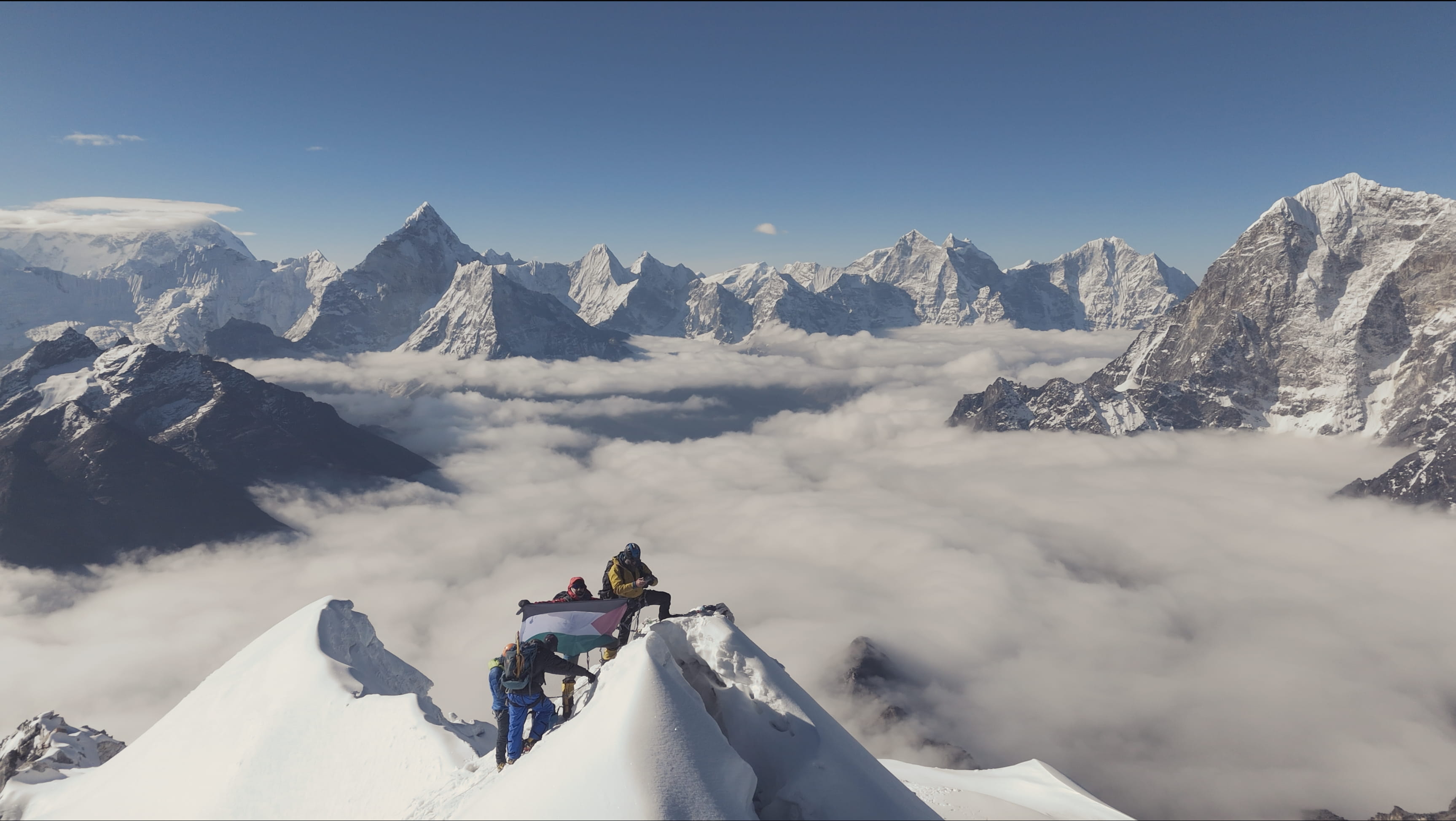 Climbers raise the Palestinian flag on a snowy summit above the clouds